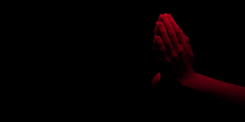 Red light on praying hands of prayer in 3D rendered illustration. Dark spotlight on finger tips. Religious black background with large copy space. Prayer's hand silhouette for poster, banner or logo