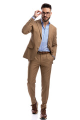 Poster - full body picture of sexy businessman looking away and fixing glasses