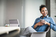 © Westend61 - Happy businesswoman with coffee cup sitting on chair in office