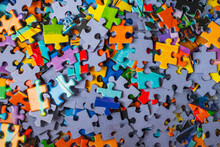 Top View Many Jigsaw Puzzle Pieces Over The Entire Frame. A Background Image Of Scattered Colorful Puzzle Pieces.