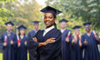 © Syda Productions - education, graduation and people concept - happy graduate student woman in mortarboard and bachelor gown over group of people on background