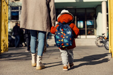 A Mother Entering The Kindergarten Yard With Her Preschooler Boy.