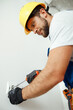 © Kostiantyn - Male worker, professional electrician in hard hat and protective gloves using screwdriver while installing electrical socket outlet