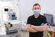 © Andriy Medvediuk - A male dentist in uniform and medical face mask poses against a background of dental equipment in a dental office. Healthy teeth and medicine concept. dentist's reception