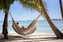 Beach Vacation Holidays With Woman Relaxing In Hammock Between Coconut Palm Tree, White Sand, Blue Sky And Turquoise Water. Scenic Island Resort In Maldives, Perfect Travel Destination.