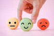 hand choose happy face icon on green macaron with blurred others on sweet pink background