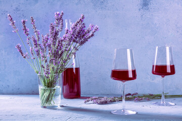 Rose wine, two glasses and a bottle, with a bouquet of fresh lavender flowers, with summer shadows on the table