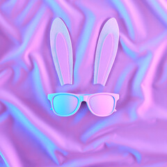 Wall Mural - Creative easter idea. Bunny rabbit ears and white tinted sunglasses on ioridescent neon background, flat lay. Concept art. Happy Easter minimal surrealism.
