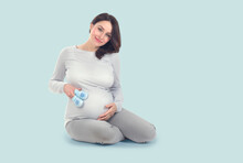 Pregnant Woman Touching Her Belly. Pregnant Middle Aged Mother's Hands Caressing Her Tummy. Healthy Pregnancy Concept, Sitting Gravid Female On Blue Background, Full Length Portrait
