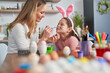© gpointstudio - Caucasian mother and daughter painting Easter bunny on her girl's face
