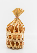 Isolated Organic Brown Chicken Eggs In Round Bamboo Wicker Basket On White Background, Front View Image. The Concept For Healthy Eating.