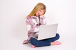 © Jihan - caucasian teen girl sitting with laptop in lotus position on white background making facepalm gesture while smiling amazed with stupid situation.