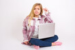 © Jihan - Upset caucasian teen girl sitting with laptop in lotus position on white background shapes little gesture with hand demonstrates something very tiny small size. Not very much