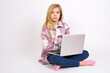 © Jihan - Picture of angry caucasian teen girl sitting with laptop in lotus position on white background looking camera.