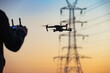 A concept of a man flying a drone collecting a data remotely from a power tower station