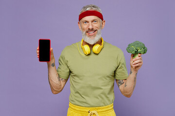 Wall Mural - Fun elderly gray-haired man 40s years old in headband khaki t-shirt hold mobile cell phone with blank screen workspace area broccoli isolated on plain pastel light purple background studio portrait.