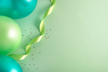 St Patricks Day party background. Balloons and festive decor on pastel green surface. Top view, flat lay, copy space