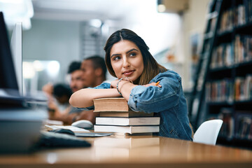 Poster - Im going to make you so proud. Shot of a young woman resting on a pile of books in a college library and looking thoughtful.