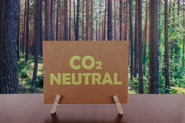 co2 neutral text on card on the table with pine forest background.