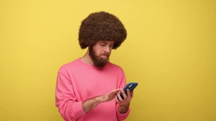 Wall Mural - bearded hipster man with afro hairstyle swiping, scrolling and typing on smartphone with smile on hi