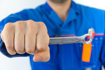 A man in blue work clothes on a white background with a construction tool in his hands.