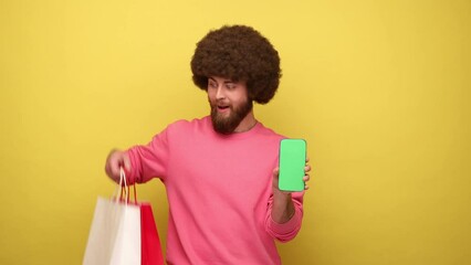 Wall Mural - hipster man with afro hairstyle showing paper bags with purchases and smartphone with empty screen, 