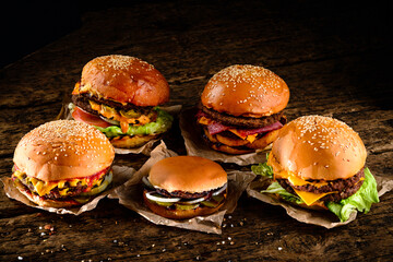 Sticker - A set of homemade delicious burgers of beef, bacon, cheese, lettuce and tomatoes on a dark background. Fat unhealthy food close-up