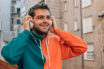 young man with headphones on city street outdoors