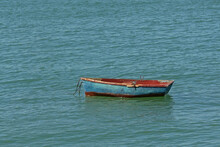 Old Worn Blue And Red Dinghy In The Sea