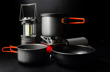 Photo Of Titanium Camping Cookware With Led Lantern And Portable Gas Stove On Black Backdrop.