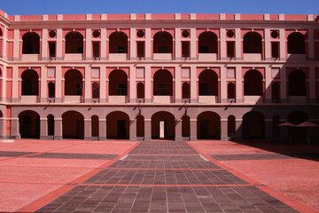 Poster - A scenic view of a pink arcade building against an empty square on a sunny day