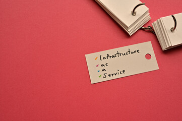 Poster - There is a small card placed on a red background paper with the word Infrastructure as a Service written on it. Copy space available.