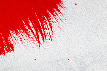 thick red bright acrylic paint applied unevenly on a light surface