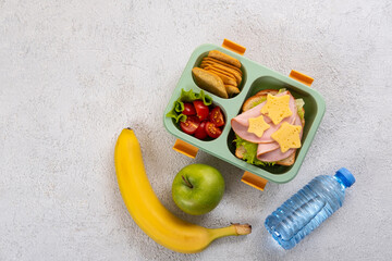 Wall Mural - Healthy school lunch box with sandwich and salad on the table. Banana, apple and a bottle of water. Back to school