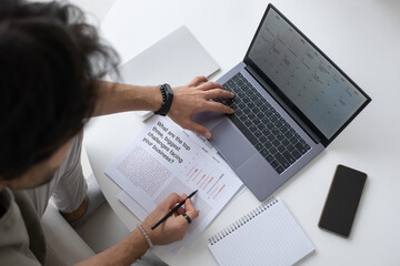 Aufkleber - Contemporary auditor or analyst looking through text in document and analyzing financial data on laptop screen while working from home
