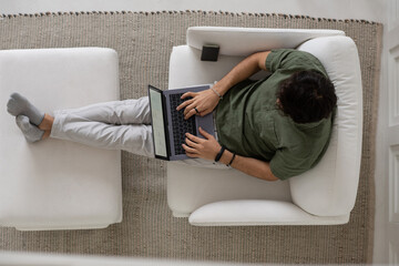 Aufkleber - Overview of young male employee typing on laptop keyboard while looking through graphic data and analyzing it during work from home