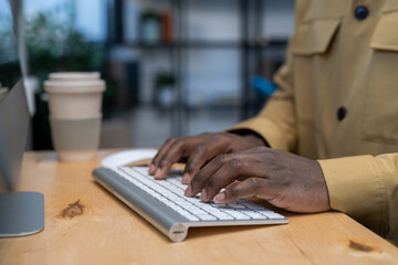 Aufkleber - Hands of young African-American businessman pressing keys of computer keyboard while working in the internet by wooden table