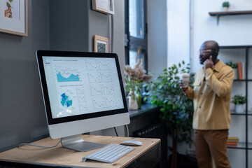 Aufkleber - Computer monitor on desk with digital financial diagram and graphs on screen on background of young businessman calling