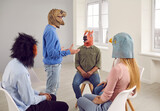 Fototapeta  - People wearing funny masks having a conversation during a group therapy session. Different male and female patients with animal faces talking, sharing their problems, and looking for solutions