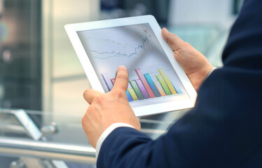 Business person analyzing financial statistics displayed on the tablet screen.