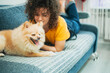 © MagicsPhotos - Curly haired woman playing with her dog at home.