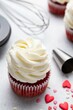 Red velvet cupcakes with cream cheese frosting on light background. Valentine's Day concept. Selective focus.