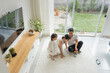 © LEONARDO BORGES - Overhead shot of a beautiful Asian family sitting on the living room carpet playing a game.