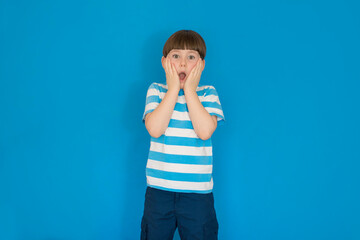 Wall Mural - Boy surprised with open mouth on a blue background.