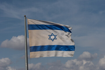 Wall Mural - A large, blue and white flag of the State of Israel rippling in the wind on a sunny day during the national observance of the Independence and Memorial day holidays.