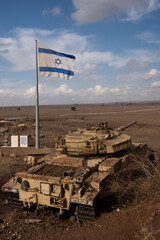 a large, blue and white flag of the state of israel rippling in the wind beside a defunct army tank 