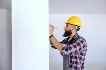 Wall Mural - A worker writing on the wall where to drill a hole for electric installations.