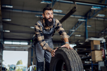 Wall Mural -  Auto-mechanic in a workshop with tire.