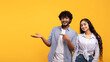 © Prostock-studio - Cheerful indian couple pointing at open palm, man demonstrating invisible object, showing copy space, panorama