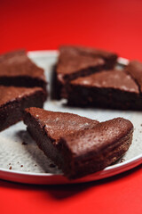 Wall Mural - Chocolate Flourless Cake on red background. Soft chocolate gateau or Brownie cake. Selective focus